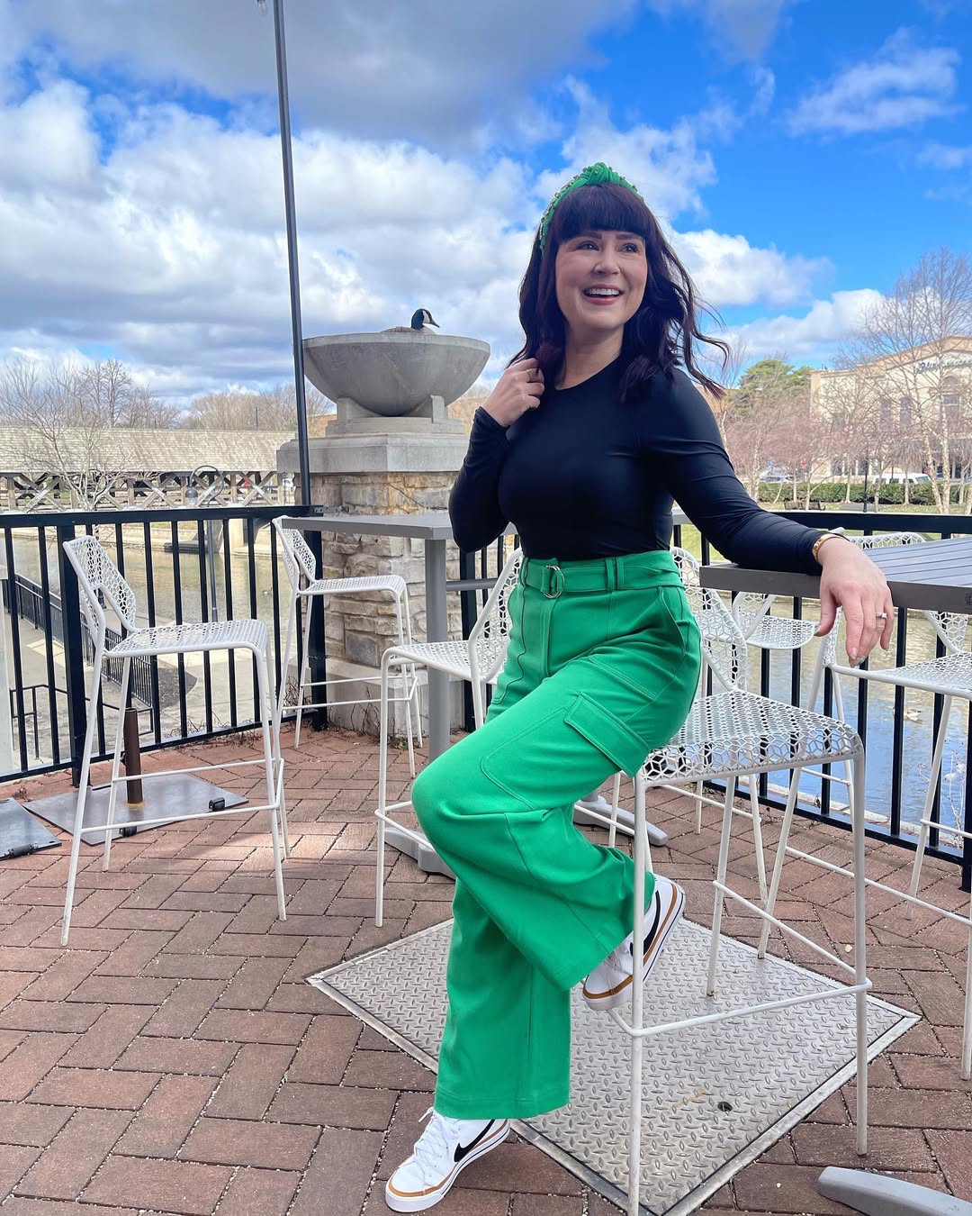 Chic green pants with black top and sneakers